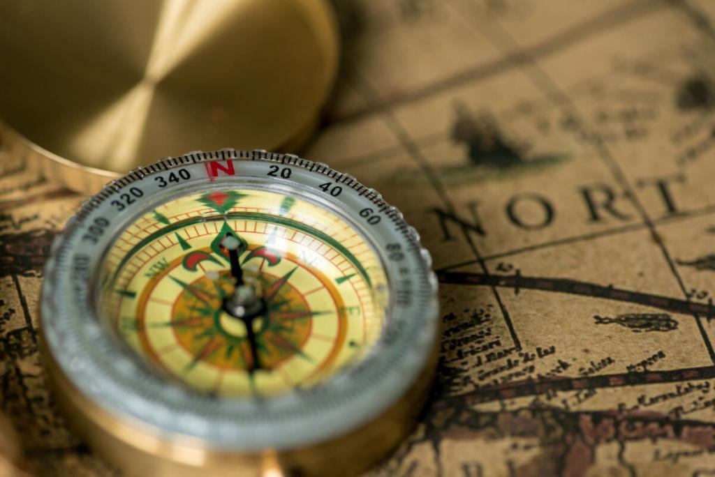 an elegant compass rests on a vintage map in a sepia tone. The compass has a brass cover that is open.
