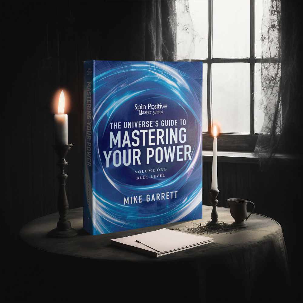 A blue book titled "The Spin Positive Master Series, Volume #1 - The Universe's Guide to Mastering Your Power" stands vertically on a small round table draped in a dark tablecloth. Lit candlesticks stand on either side. A notepad and paper lay on the table in front of the book. A small teacup sits next to the candlestick on the right. A six-pane window lights the dark scene from behind.