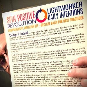 Mojoe Mike peeks from behind a laminated copy of the Spin Positive Revolution Intention Set