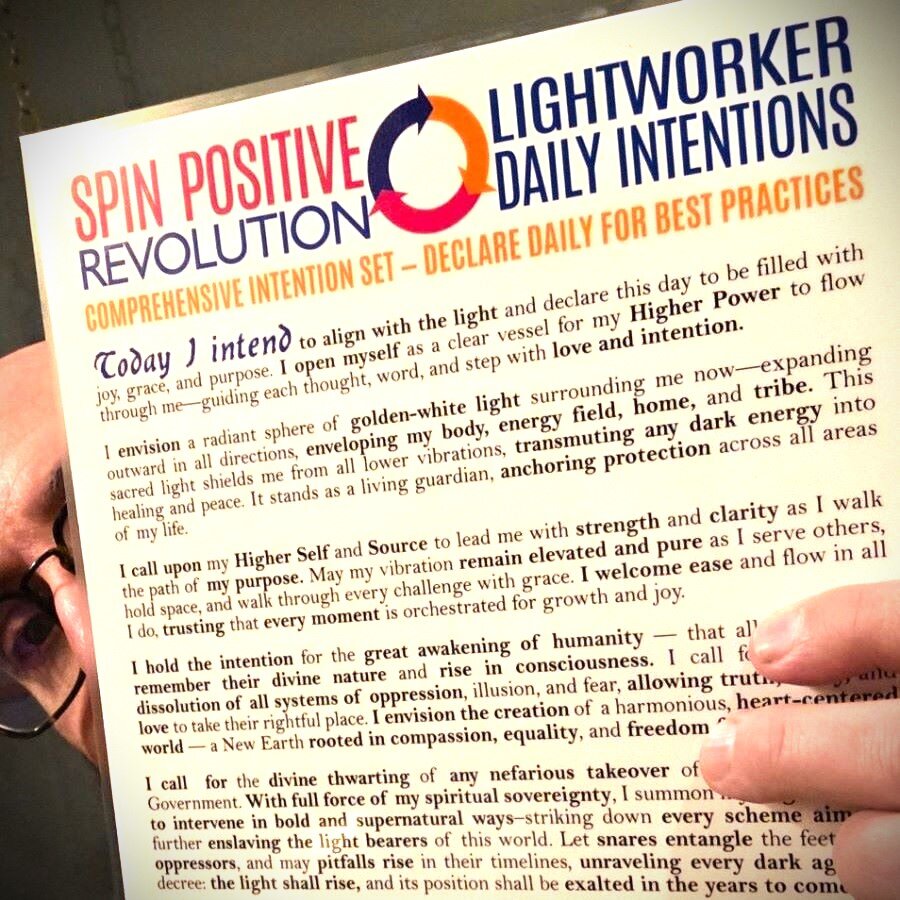 Mojoe Mike peeks from behind a laminated copy of the Spin Positive Revolution Intention Set